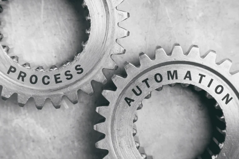 Imagem de duas engrenagens metálicas interligadas. Uma engrenagem possui a palavra 'PROCESS' e a outra, a palavra 'AUTOMATION', simbolizando a automação de processos, para ilustrar artigo sobre Power Automate.