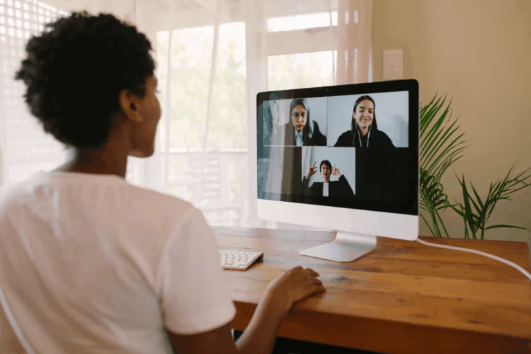 foto de mulher negra fazendo reunião em vídeo, em um Mac, com outras três mulheres ilustra artigo sobre segurança no Skype para chamadas de vídeo