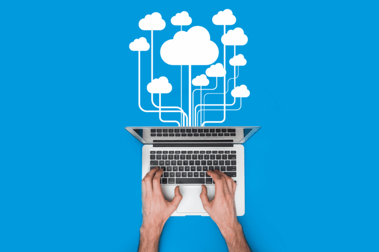 imagem de laptop com as mãos de uma pessoa digitando no teclado, com ícones de nuvens conectados ao dispositivo, sobre um fundo azul, ilustra artigo sobre migração para cloud computing.