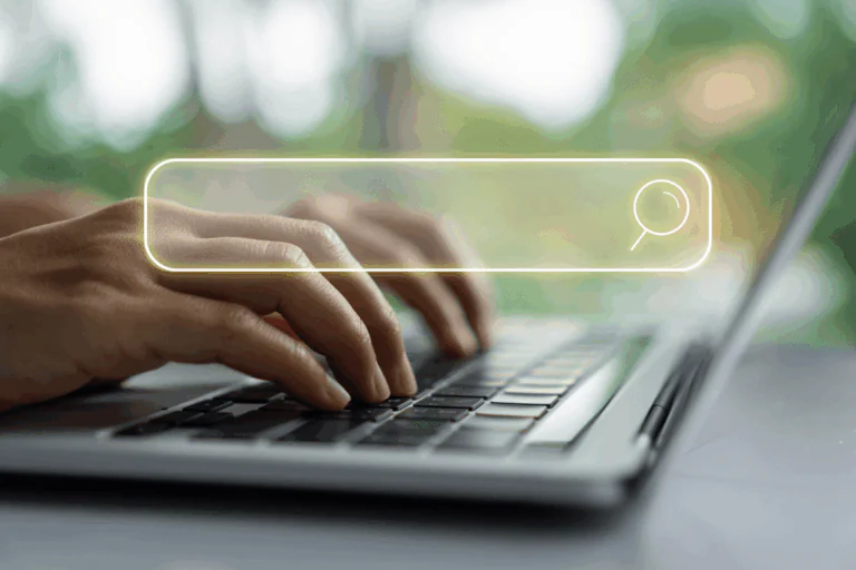 ilustrando artigo sobre navegar de forma segura e evitar sites maliciosos, a foto traz mãos femininas digitando em um teclado de laptop, com um campo de busca iluminado sobreposto na imagem.