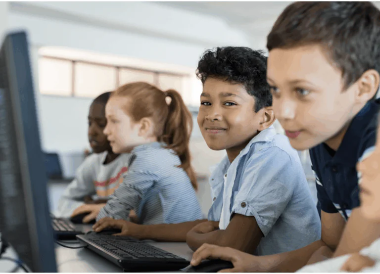 crianças estudantes, enfileiradas, em frente a computadores interligados, demonstrando a importância de se utilizar sistemas Microsoft nas instituições de ensino.